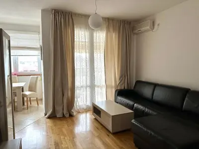 a living room with a black leather couch and a table at Light Bar Apartment in Bar