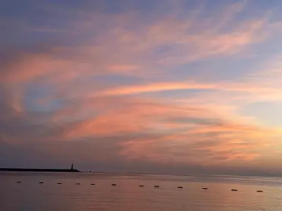 a cloudy sky over a body of water with a lighthouse at Light Bar Apartment in Bar