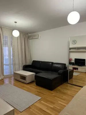 a living room with a black leather couch and a mirror at Light Bar Apartment in Bar