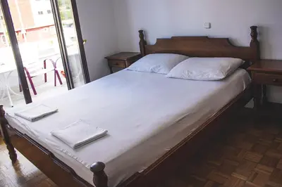 a bed with white sheets and white pillows on it at Vera Apartments in Budva