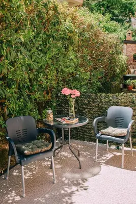 two chairs and a table with a vase of flowers on a patio at Lovely apartment Moki near the center in Kotor