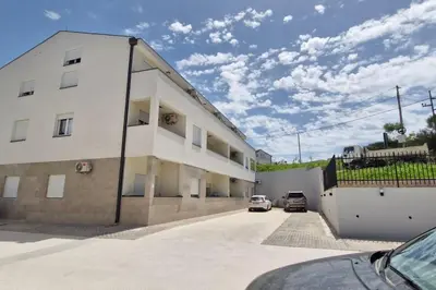 a white building with two cars parked in a parking lot at Zira in Kotor