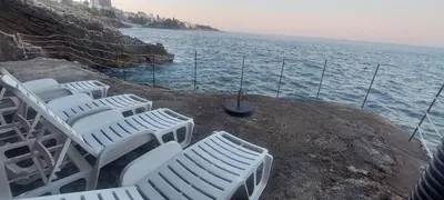 a group of white chairs sitting on the edge of the water at Sea Cliff Villa in Bar