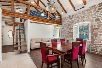 a living room with a wooden table and red chairs at Seaside Stone House - Bella Vista in Kotor