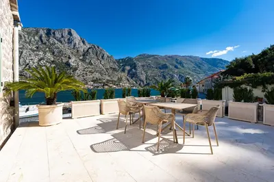 a table and chairs on a patio with a view of the water at Seaside Stone House - Bella Vista in Kotor