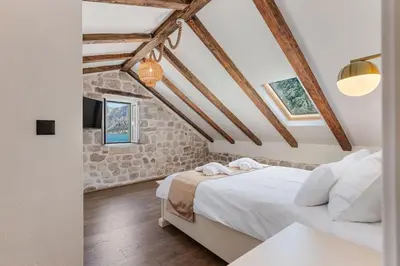 a bedroom with a bed in a room with exposed ceilings at Seaside Stone House - Bella Vista in Kotor