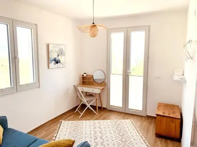 a living room with white walls and windows and a blue couch at Chalet Elli's Mountain View in Velje Selo