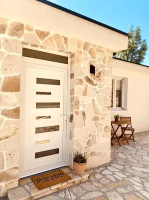 a white door on a stone building with a table at Chalet Elli's Mountain View in Velje Selo