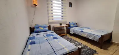a room with two beds and a table with a night stand at Apartment Belis Utjeha in Utjeha