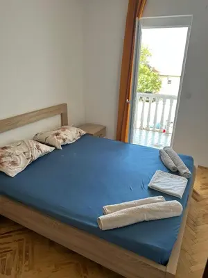 a bedroom with a bed with blue sheets and a window at Oliva apartment in Petrovac na Moru