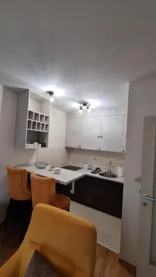 a kitchen with white cabinets and orange chairs at Mara's cozy apartment in Podgorica