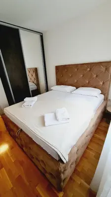 a large bed with two white towels on it at Mara's cozy apartment in Podgorica