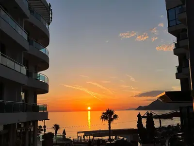 a sunset over the ocean in a city with buildings at Kolibri Apartment in Dobra Voda
