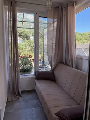 a couch in a room with a large window at Kolibri Apartment in Dobra Voda