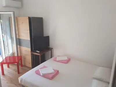 a room with a bed and a tv and a red chair at Apartmani Dream 3 in Bar, Susanj