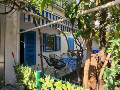 a house with blue shutters and chairs in the yard at Hostel Budva in Budva