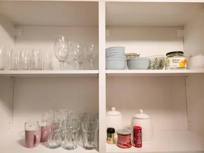 a cabinet filled with glasses and plates and bottles at Hostel Budva in Budva