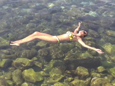 a woman in a bikini swimming in the water at Apart Yukka first line in Utjeha