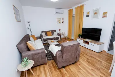 a living room with a couch and two chairs and a television at Elegant Escape Podgorica in Podgorica