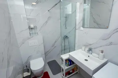 a white bathroom with a sink and a shower at Elegant Escape Podgorica in Podgorica