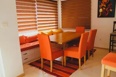 a dining room with a wooden table and orange chairs at Mantra HOME in Bar