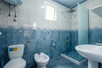 a blue and white bathroom with a toilet and a sink at Kraja Apartments in Ulcinj