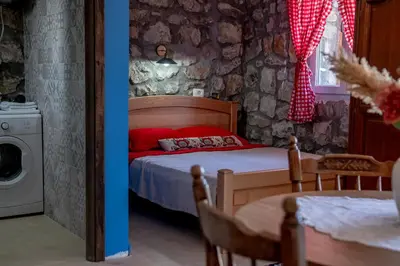 a bedroom with a bed with red pillows and a table at Stara Kruska in Podgorica