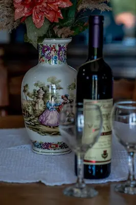 a bottle of wine next to a vase and two glasses at Stara Kruska in Podgorica