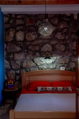 a bed in a room with a stone wall at Stara Kruska in Podgorica