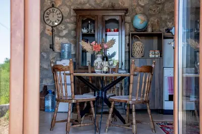 a dining room table with two chairs and a clock at Stara Kruska in Podgorica