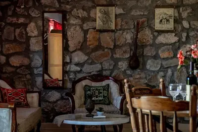 a room with a table and chairs and a stone wall at Stara Kruska in Podgorica