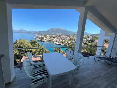 a table and chairs on a balcony with a view of the water at Jakovljevic apartman in Utjeha