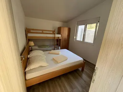 a small bedroom with a bunk bed and a window at Jakovljevic apartman in Utjeha