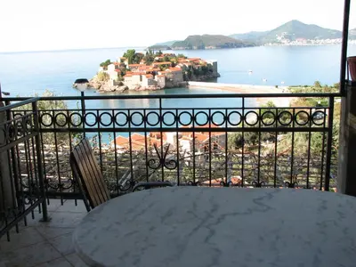 a table on a balcony with a view of the ocean at Guest House Ivo Jovanovic in Sveti Stefan