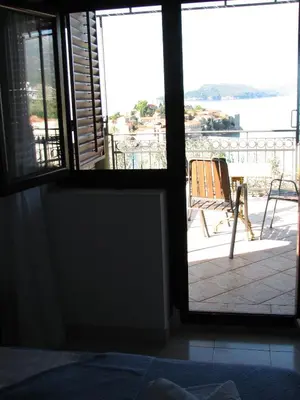 a bedroom with a door open to a balcony with a chair at Guest House Ivo Jovanovic in Sveti Stefan