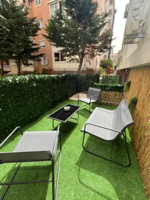 three chairs and a table on a yard with grass at One bedroom apartments Budva in Budva