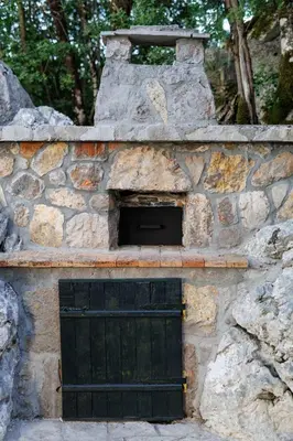 a stone building with a black door and a stone wall at Oasis of Peace Meterizi in Cetinje