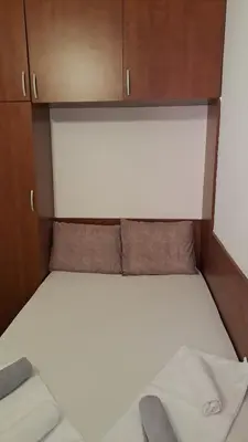 a small bed in a small room with wooden cabinets at Apartman Vesna Budva 1 in Budva