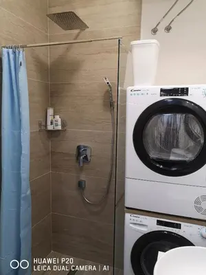 a bathroom with a washing machine and a shower at Život je tren in Podgorica