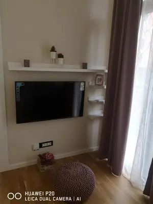 a flat screen tv on a wall in a living room at Život je tren in Podgorica