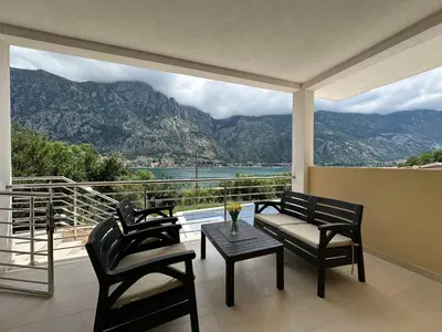 a balcony with chairs and a table and a view of the mountains at Luxury Kotor bay view studio in Muo
