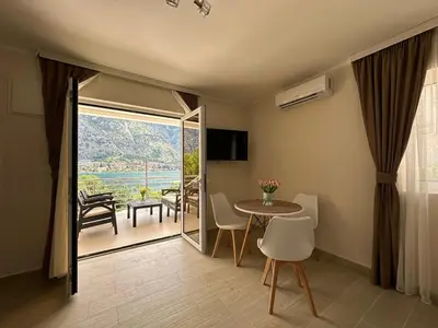 a living room with a table and chairs and a balcony at Luxury Kotor bay view studio in Muo