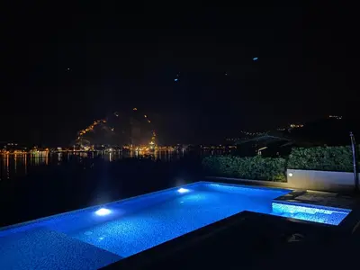 a swimming pool in the middle of the water at night at Luxury Kotor bay view studio in Muo