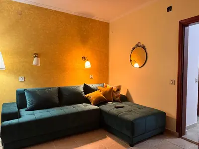 a living room with a green couch and a mirror at Villa M in Becici