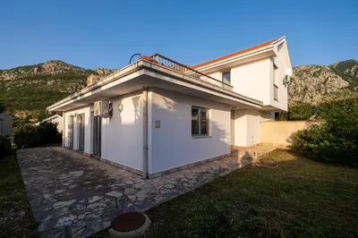 a white house with mountains in the background at Carsko Selo Budva Blizikuce Soppp in Ðenaši