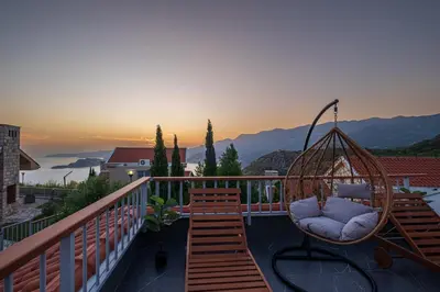 a swing on a balcony with a sunset in the background at Carsko Selo Budva Blizikuce Soppp in Ðenaši