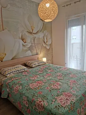 a bedroom with a bed with a flower mural on the wall at Vacation Apartment City Kvart in Podgorica