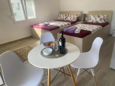 a room with two beds and a table and chairs at Jeja Apartments in Sutomore