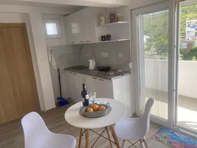 a kitchen with a table with a bowl of fruit on it at Jeja Apartments in Sutomore