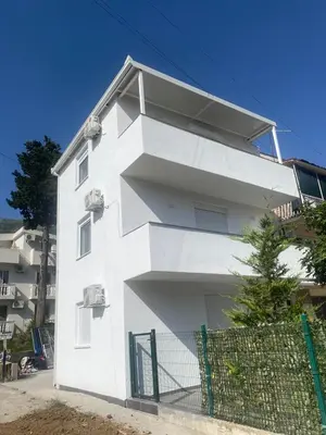 a white building with a fence in front of it at Jeja Apartments in Sutomore